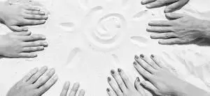 Руки реабилитированных пациентов на песке 